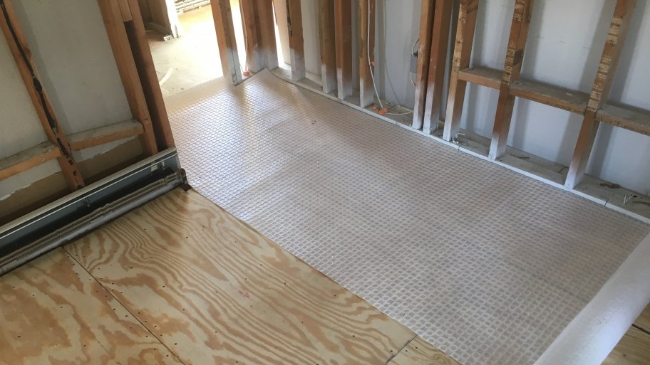 uncoupling membrane rolled out over a plywood floor.